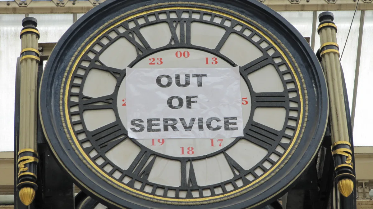 Un gran reloj de estación, sin manecillas, con un folio pegado en la esfera en el que se lee OUT OF SERVICE