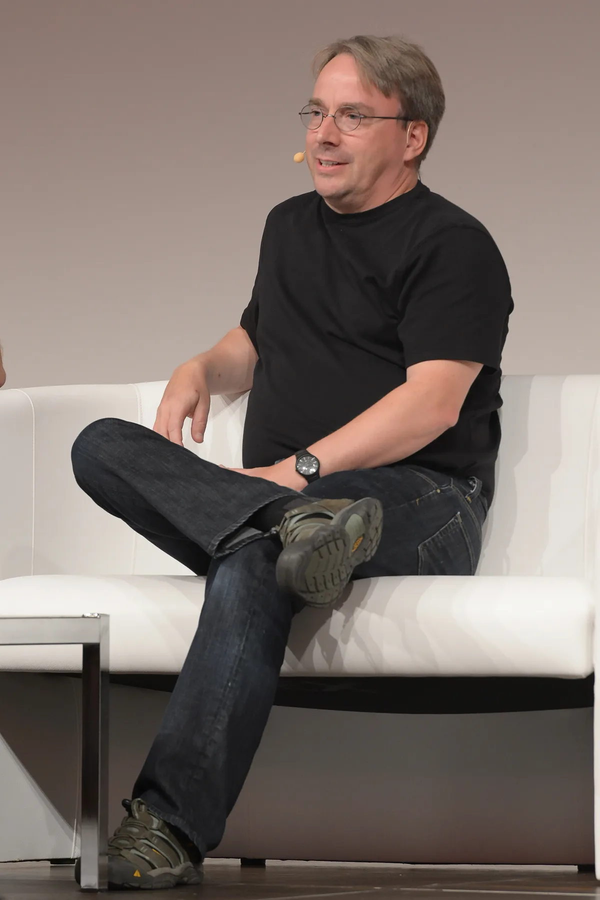 Linus Torvalds hablando sentado en un escenario, con micrófono de solapa