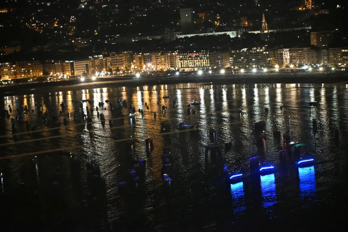 La bahía de la Concha vista de noche desde lo alto del monte Igueldo, con el paseo abarrotado, los edificios iluminados y decenas de barcos fondeados sobre el agua