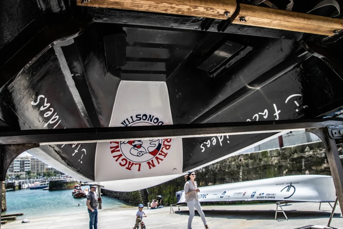 Casco de una trainera visto desde abajo, con el escudo de Arraun Lagunak y el logo de Factor Ideas pintados