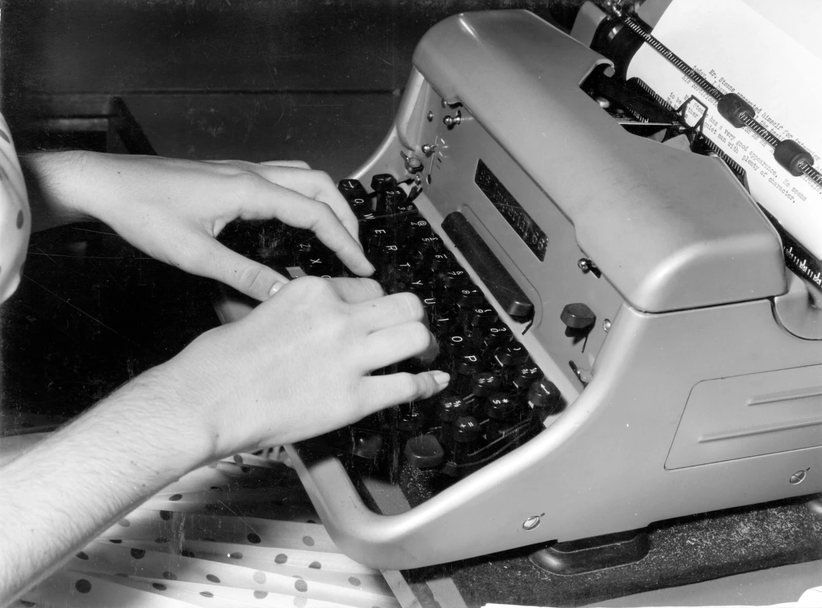 Fotografía antigua de unas manos sobre el teclado de una máquina de escribir, en posición de mecanografía