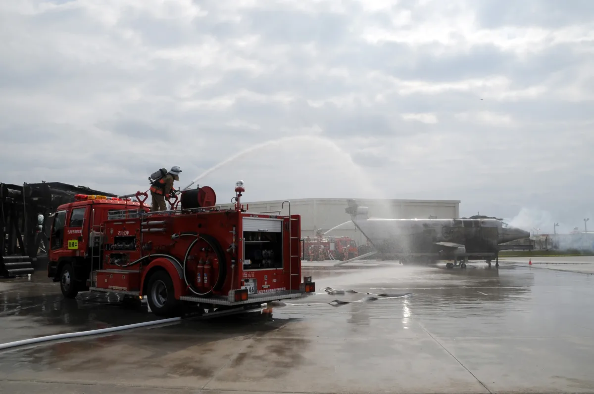 Bomberos con equipo completo apagando un fuego durante un simulacro